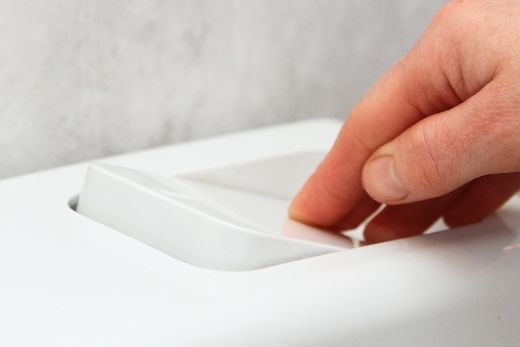 Hand drückt Spülkastentaste